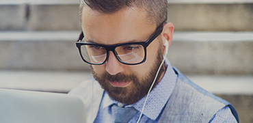 A man looking at a laptop while sitting on some stairs