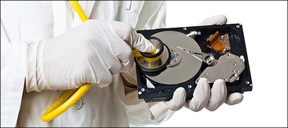 Man holding a stethoscope up to a hard drive